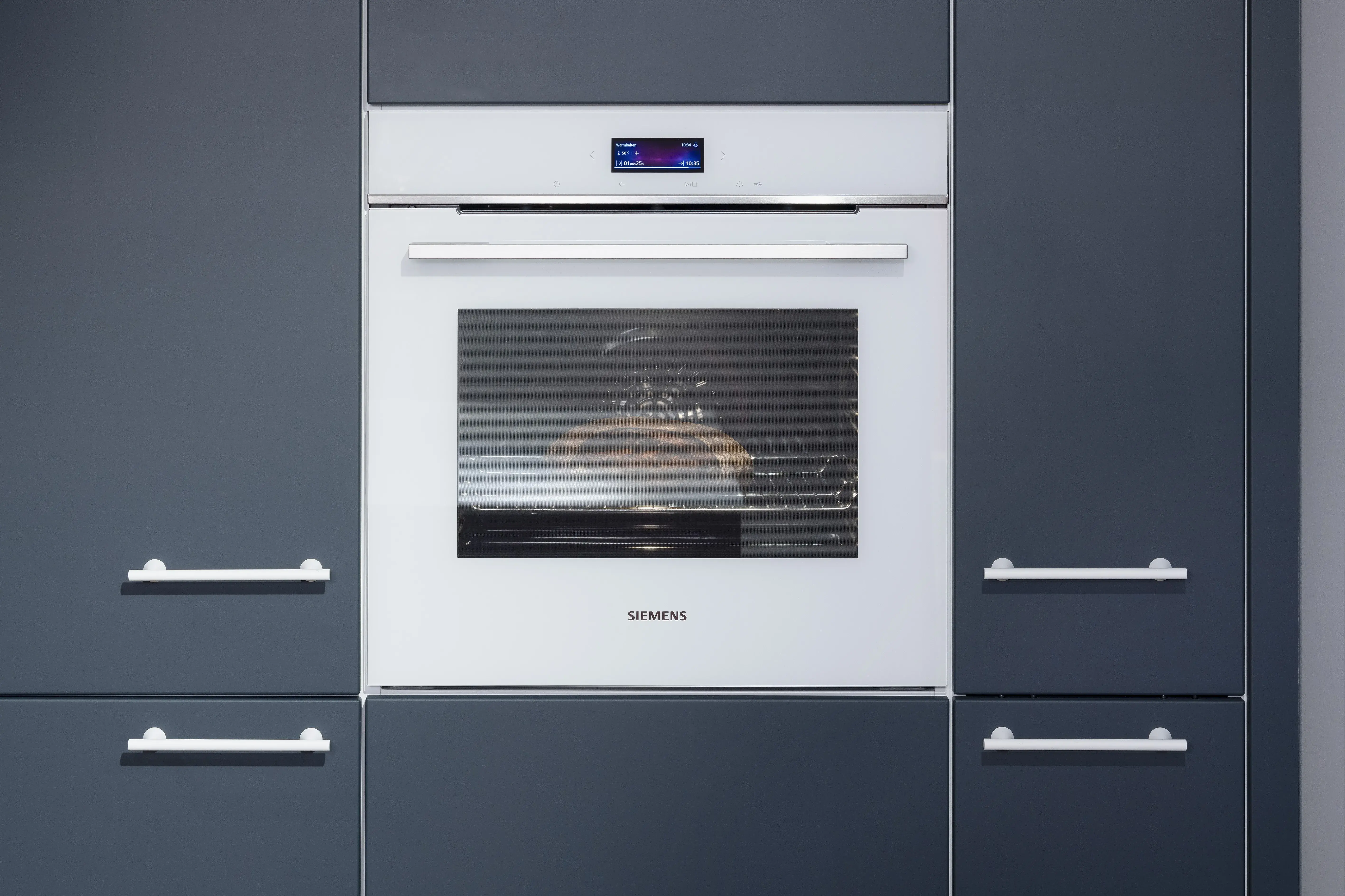 APL: Systeme Blanco Zeus matt Front: Herbstrot samtmatt AFP Front: Tiefblau samtmatt AFP Korpus: Kristallweiß/Naturweiß Griff: Metall Weiß lackiert Geräte: Siemens, Abzugshaube Airforce Armatur: Franke Spüle: Franke   Features: Farbe in der Küche, quadratische Kücheninsel mit Kochfeld und Dunstabzug, Kontrastelemente in Weiß (Griffe, APL, Spüle, Wasserhahn und Backofen), weißer BACKOFEN, kleine Designküche, junge Küche, Nischenrückwand als Motivfliese (Schüller), Arbeitsplatz, „versteckte“ Kaffeeküche 